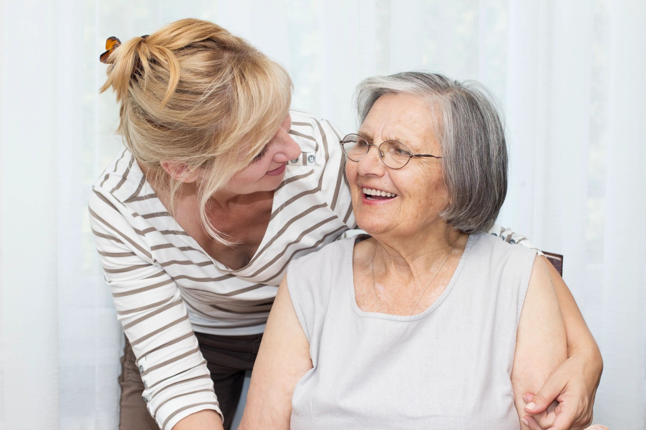 A lady looking at an old lady and smiling